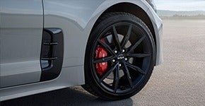 Close-up of car wheel with black alloy rim and red brake caliper