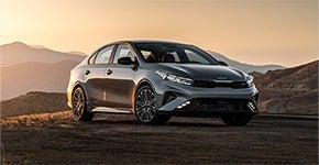 Kia parked on dusky terrain with mountains in the background